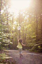 Girl playing with butterfly net in forest