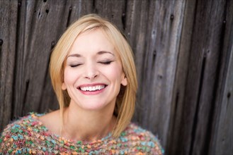 Close up of Caucasian woman laughing with eyes closed