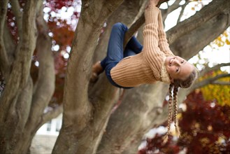 Low angle view of smiling girl climbing tree