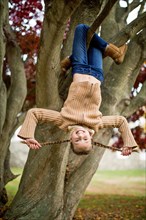 Smiling girl hanging upside-down in tree