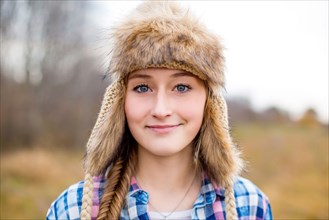 Caucasian teenage girl wearing fur hat in field