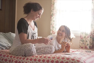 Caucasian mother and daughter playing cards in bedroom