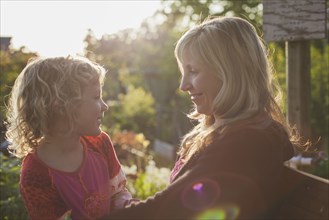 Caucasian mother and daughter smiling in garden