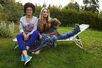 Teenagers and boy relaxing on lawn chair