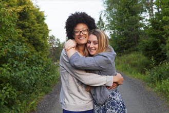 Teenage girls hugging on dirt path