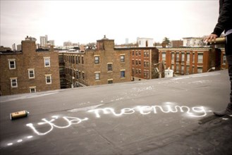 Graffiti artist spray painting on urban rooftop