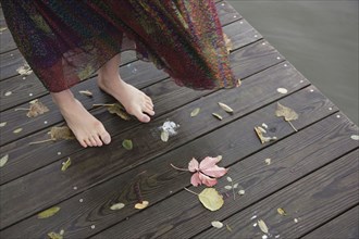 Woman standing barefoot on wooden dock