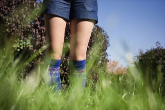 Woman wearing shorts and socks in tall grass