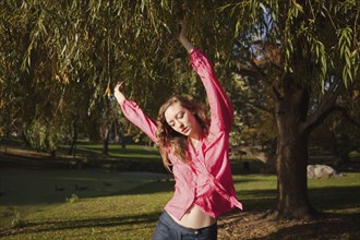 Woman dancing under tree in park