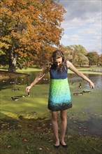 Woman wearing dress near duck pond in park