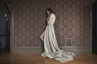 Woman covering herself with blanket by wall