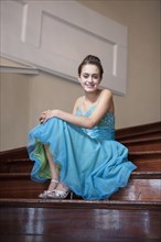 Caucasian teenage girl wearing formal dress on steps