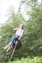 Teenage girl swinging on rope swing