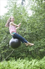 Teenage girl swinging on rope swing