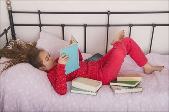 Caucasian girl reading books on bed