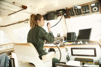 Woman using walkie-talkie and steering boat