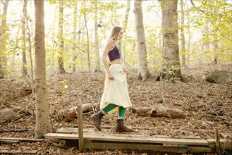 Woman walking on wooden walkway in forest