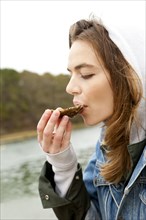 Woman eating fresh oyster at lake