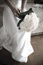 Bride with bouquet sitting on bed