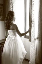 Caucasian bride looking out window