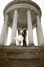 Caucasian bride and groom hugging under columns