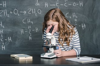Caucasian student using microscope in science class