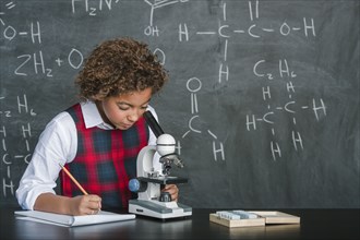 Mixed race student using microscope in science class