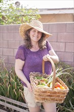 Mixed race gardener gathering vegetables in garden