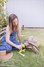 Mixed race farmer feeding tortoise in garden