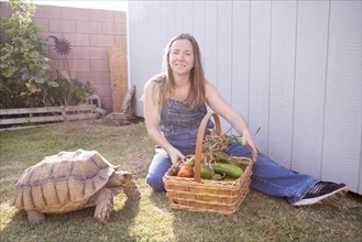 Mixed race farmer and tortoise basket of vegetables