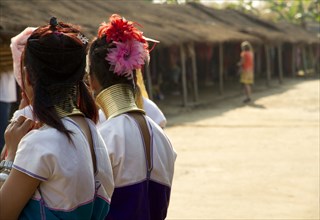 Students wearing traditional jewelry near huts
