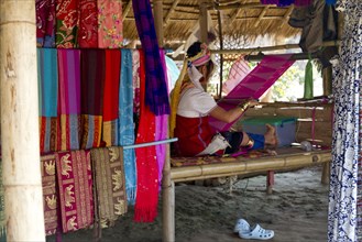 Woman weaving fabric on traditional loom in studio