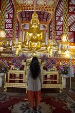 Woman admiring Buddha statue in temple