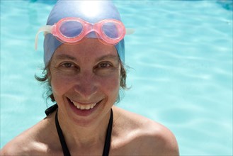 Caucasian woman in goggles and swim cap by swimming pool