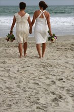 Lesbian brides holding hands on beach