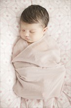 Caucasian baby girl swaddled in blanket