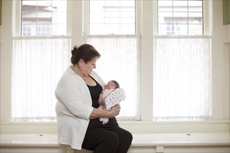 Caucasian woman holding baby granddaughter in windowsill