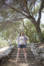 Pregnant Caucasian woman standing on hillside steps