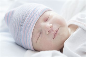 Caucasian newborn girl wearing cap