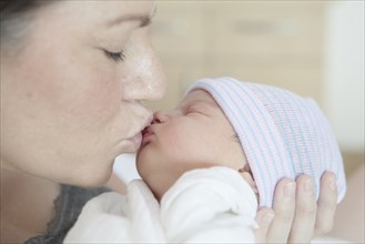 Caucasian mother kissing newborn daughter