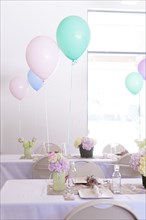 Place settings on party tables under balloons