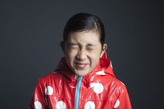 Blinking Asian girl wearing raincoat