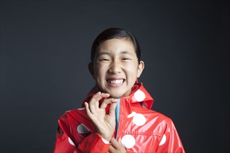 Laughing Asian girl zipping up raincoat