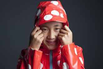 Smiling Asian girl wearing hooded raincoat