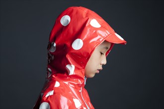 Disappointed Asian girl wearing hooded raincoat