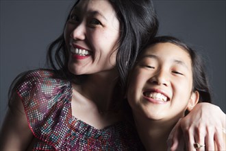 Smiling Asian mother and daughter hugging