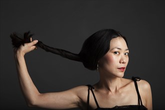 Asian woman twisting her hair in ponytail