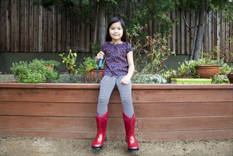 Mixed race girl wearing rain boots in backyard