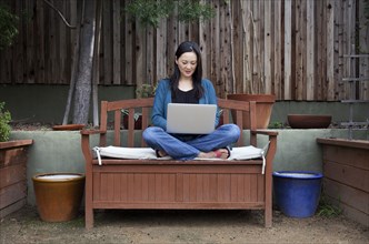 Korean woman using laptop in backyard