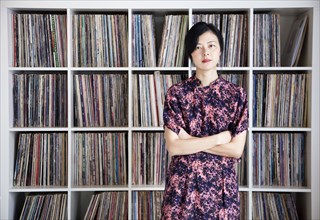 Taiwanese woman standing near record collection